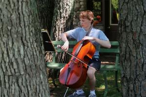 A cellist rehearses outside a practice cabin.