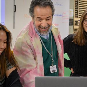 students and faculty smile at a computer in physics class at interlochen arts academy