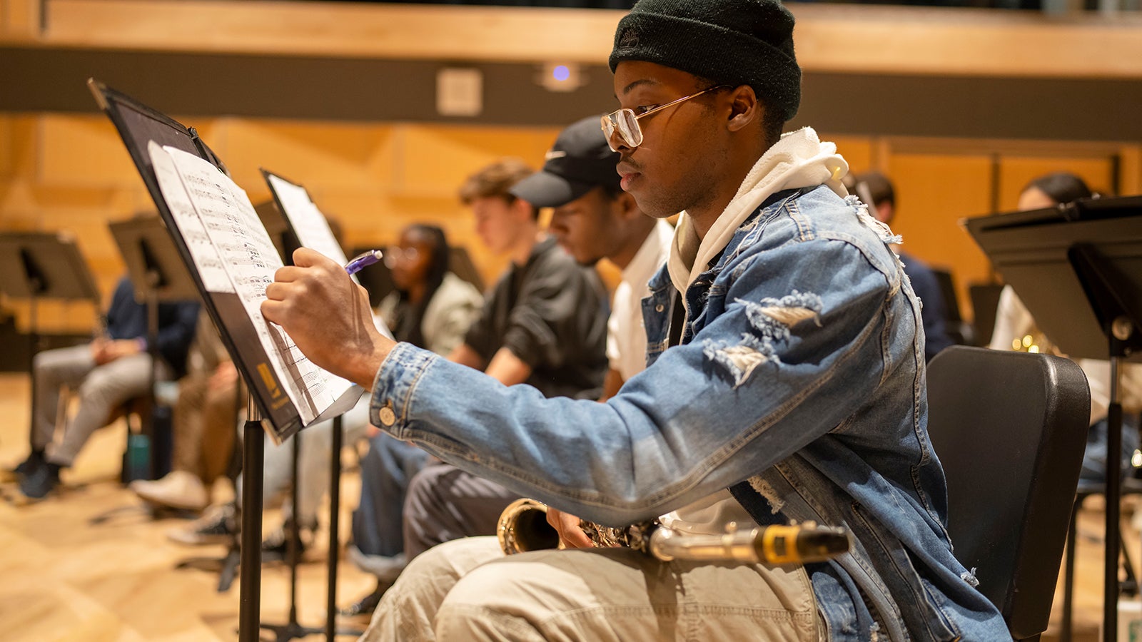 A saxophonist writes on his music during a rehearsal.