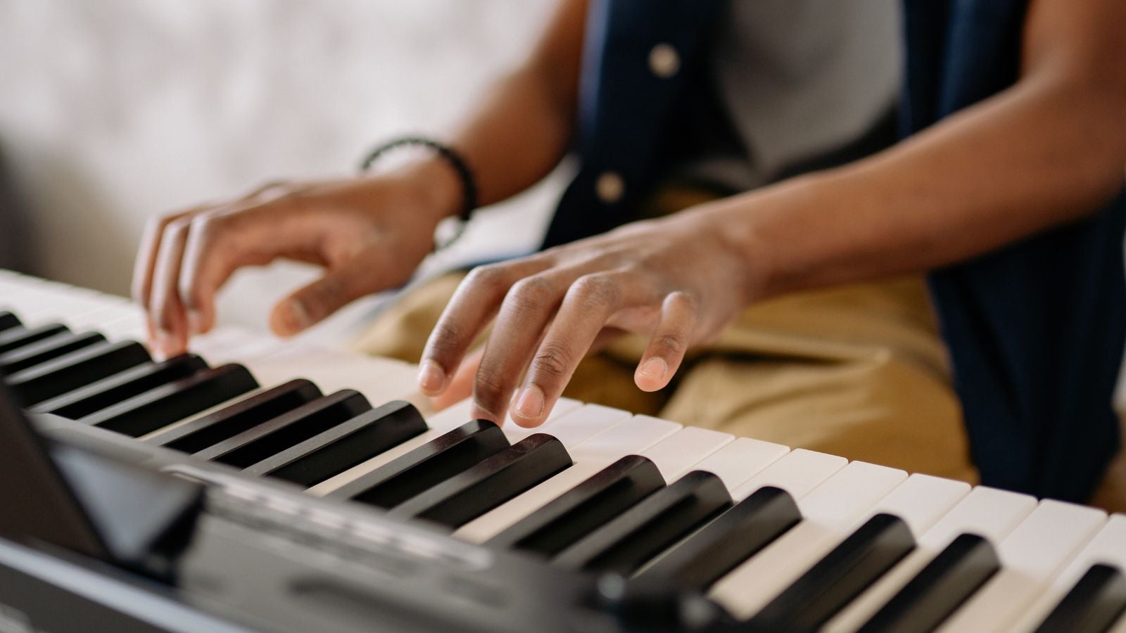 A student playing on a piano keyboard.