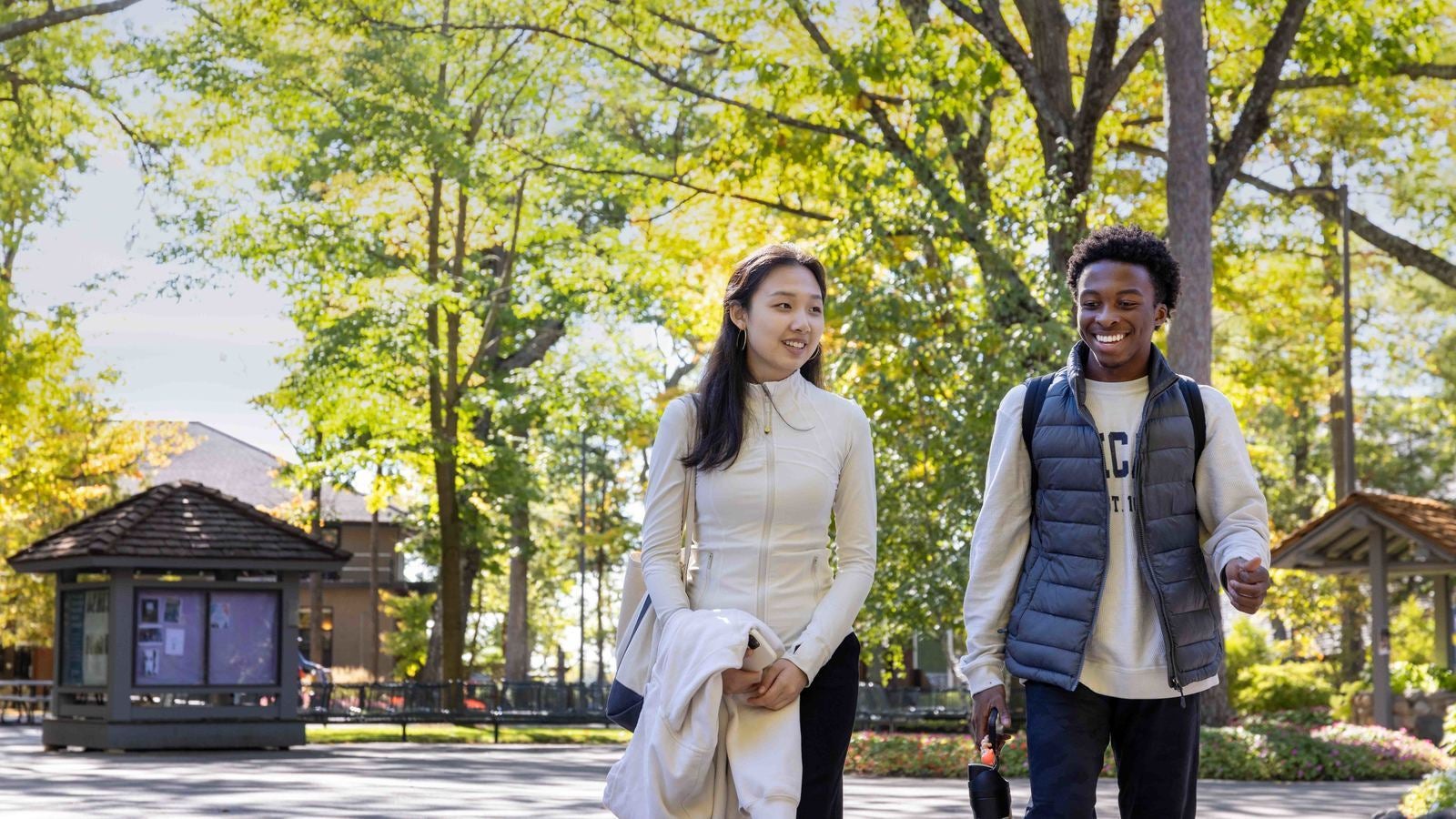 Two Interlochen Arts Academy students smile and walk to class on campus.
