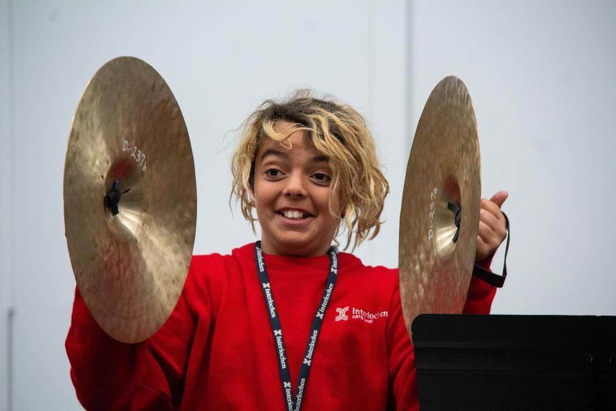 Interlochen Arts Camp student plays the cymbals while smiling