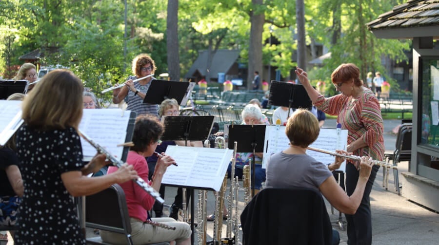 People playing flutes together in an orchestra outdoors