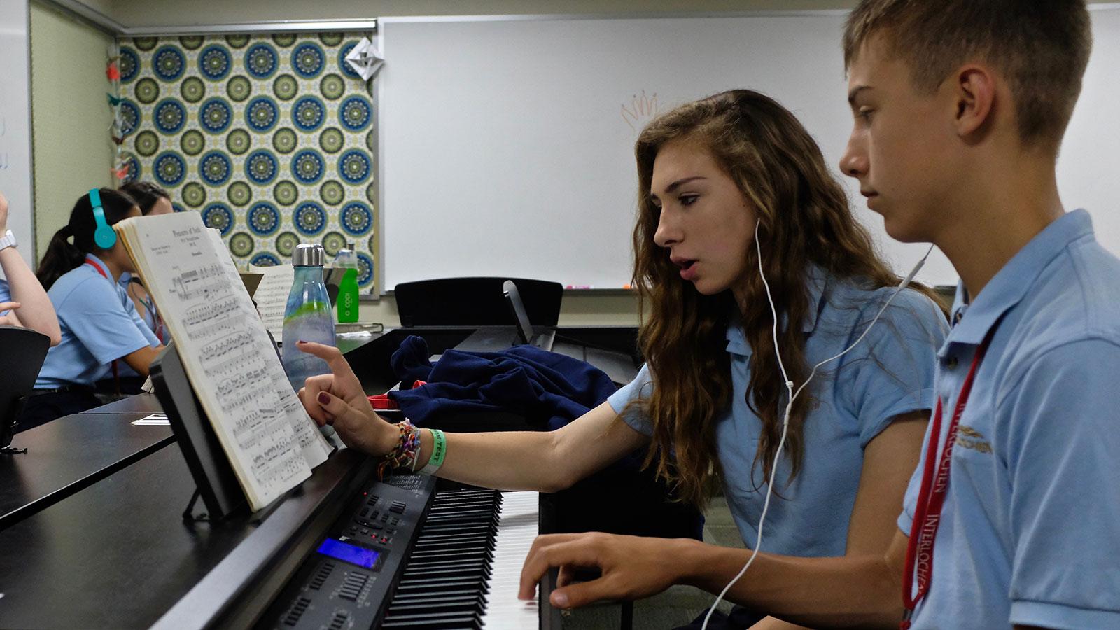 A girl and boy at an electric piano