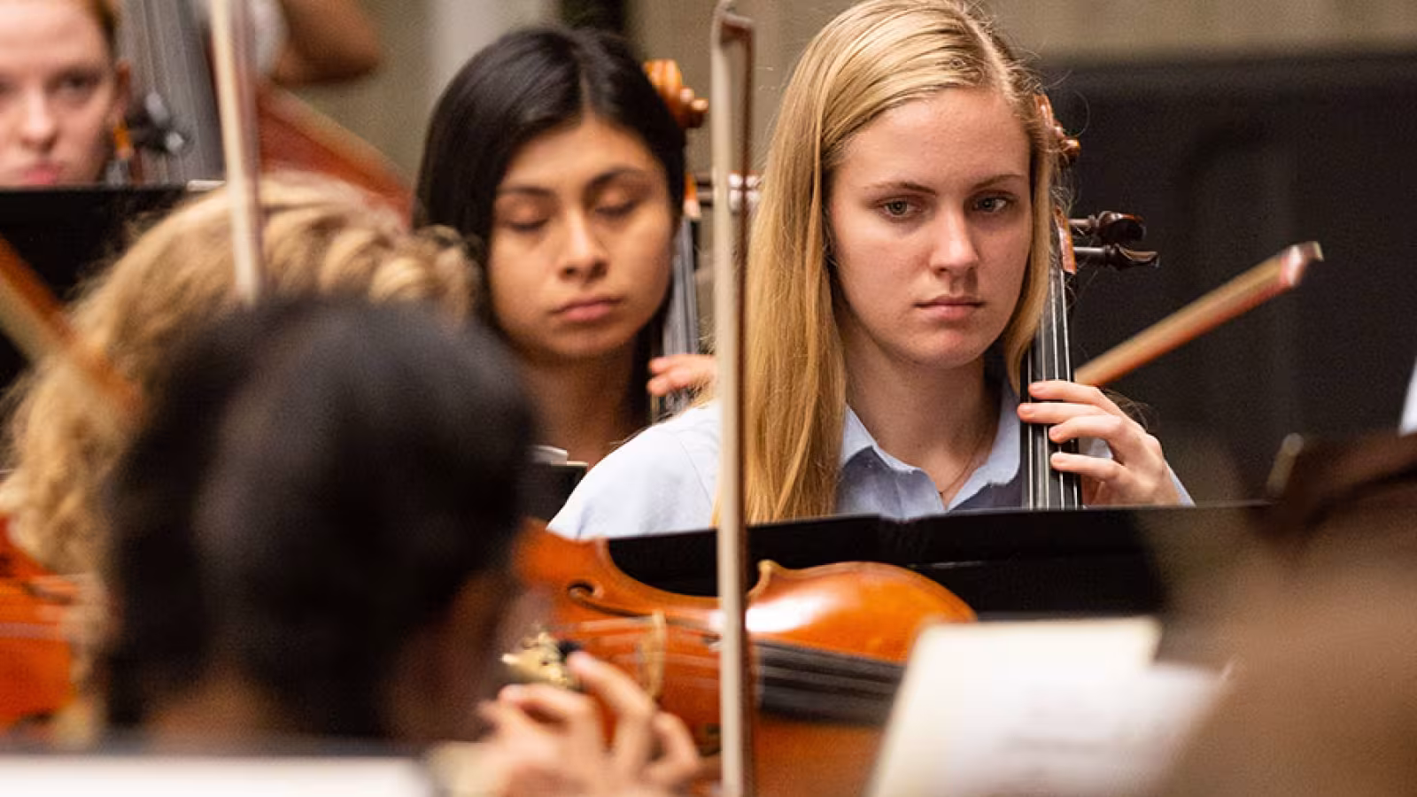 A cellist rehearses with an orchestra