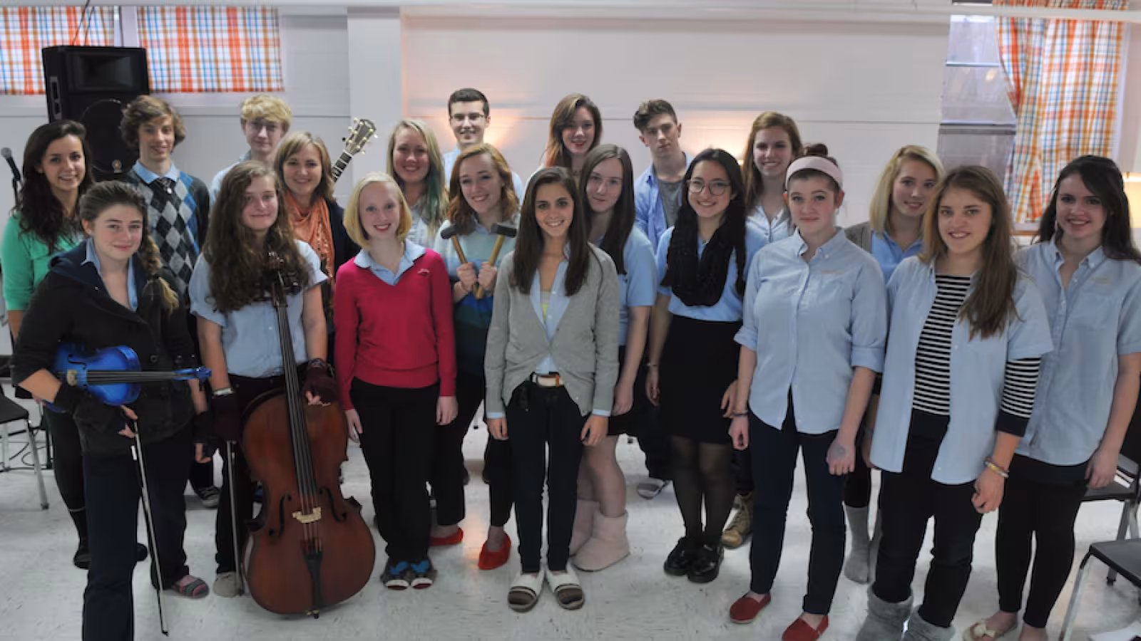 A group of 20 young people with instruments stand in a group. 