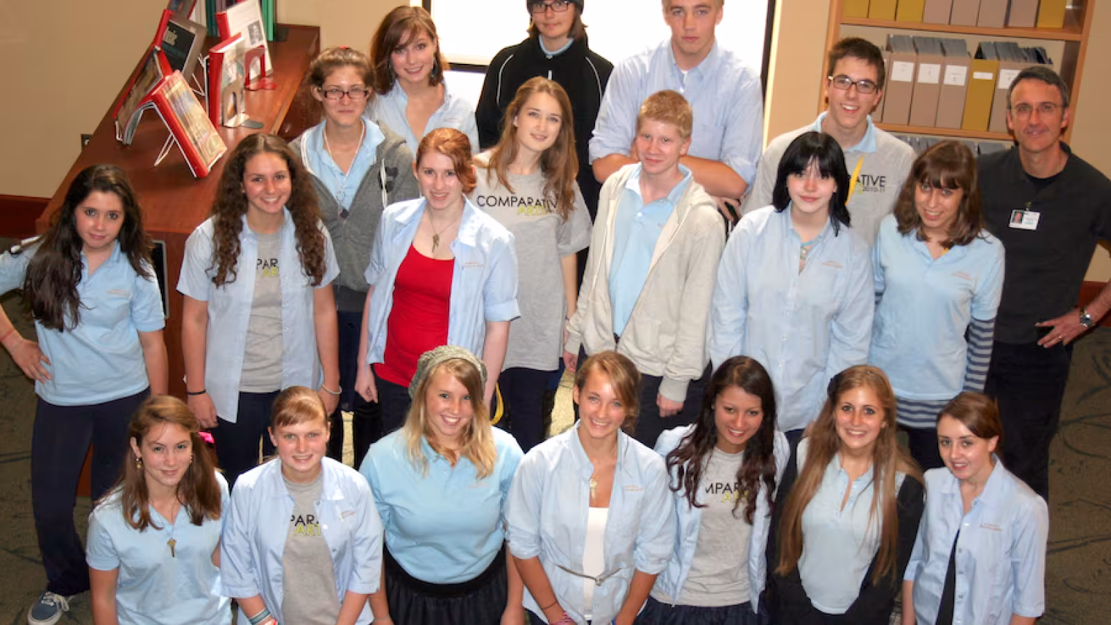 A group of nineteen students and one adult pose for a group photograph. 