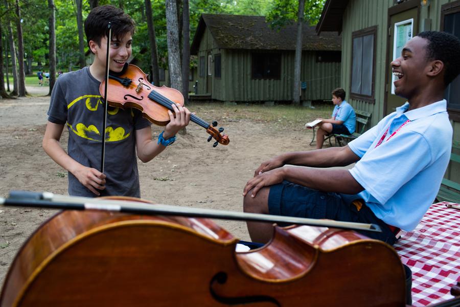 Two musicians play instruments outside their cabins
