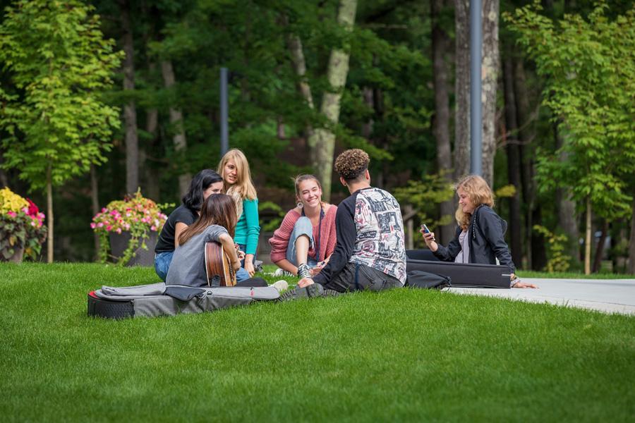 interlochen arts academy students gathered on the lawn playing guitar
