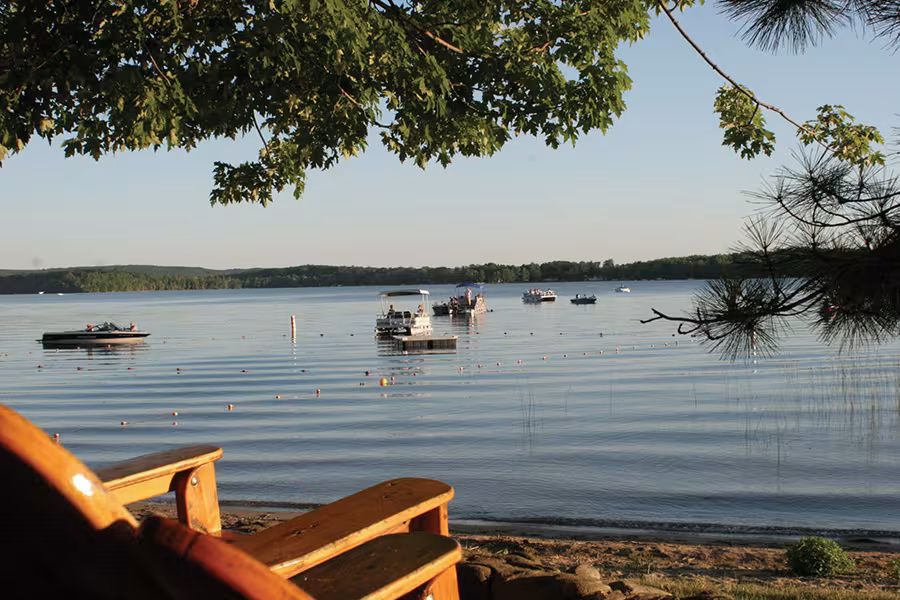 Several boats float on a gently rippling lake