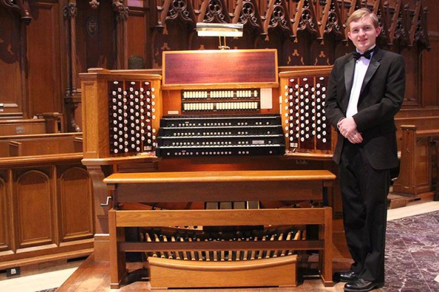 A boy poses with an organ console