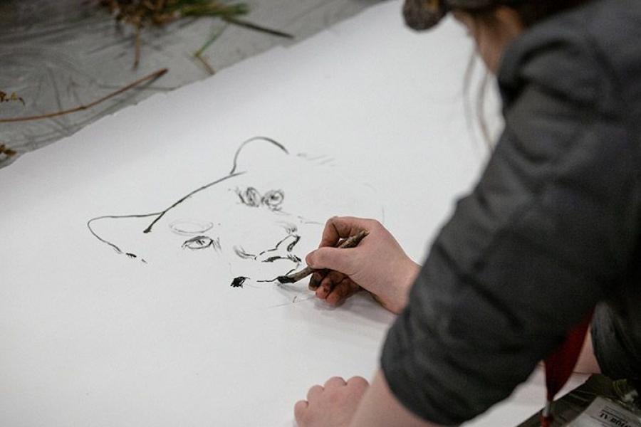 A student paints a tiger using a handmade brush.