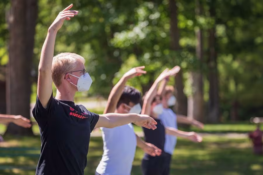 Masked dancers rehearse on a tennis court