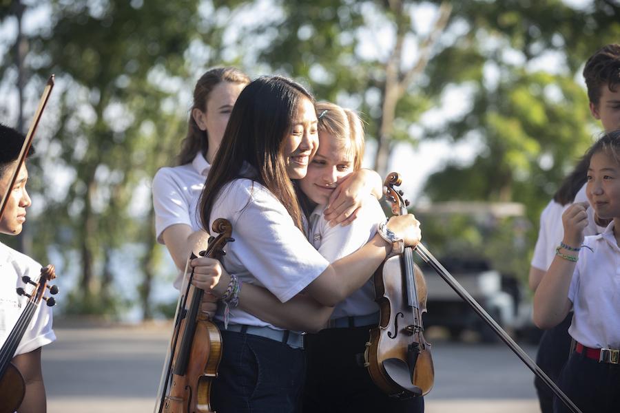 Girls hugging with violins