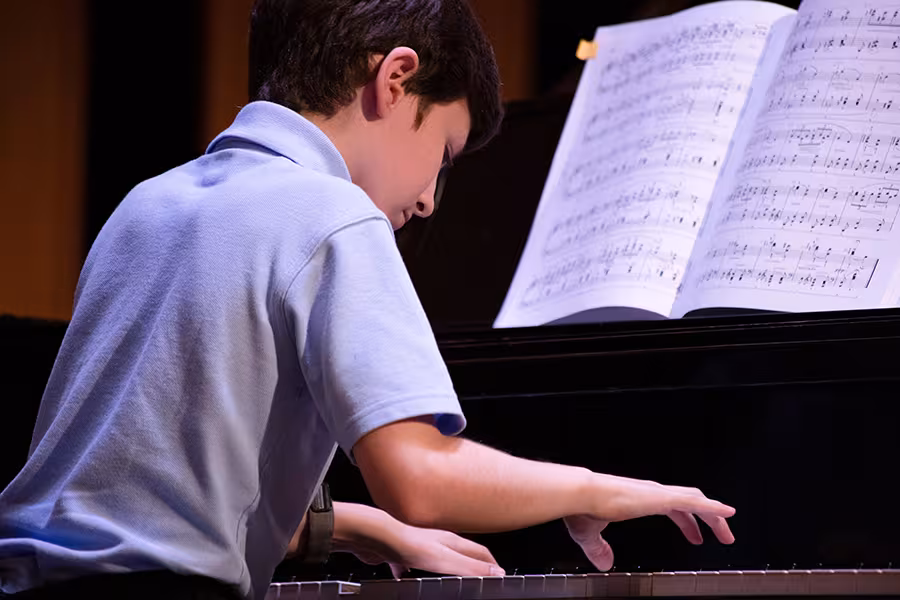 An intermediate pianist performs for his peers during class.