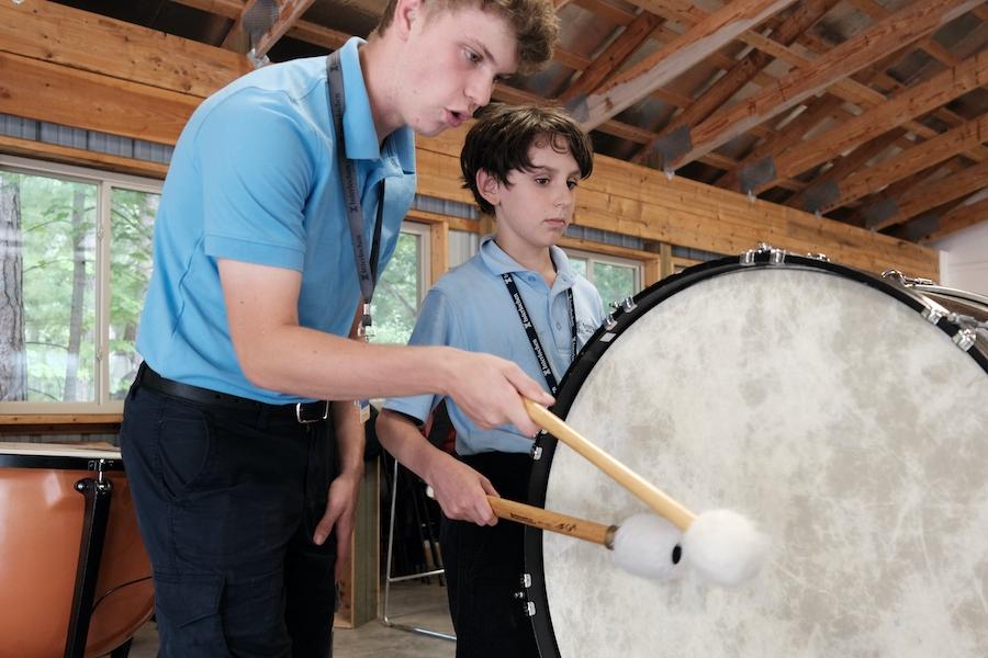 Junior Interlochen Arts Camp student plays bass drum with instructor
