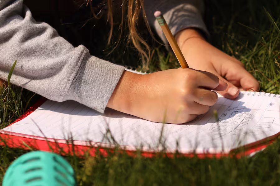 Girl writing in a notebook in the grass