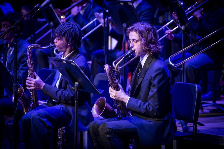 Two student saxophonists perform, dressed in suits.
