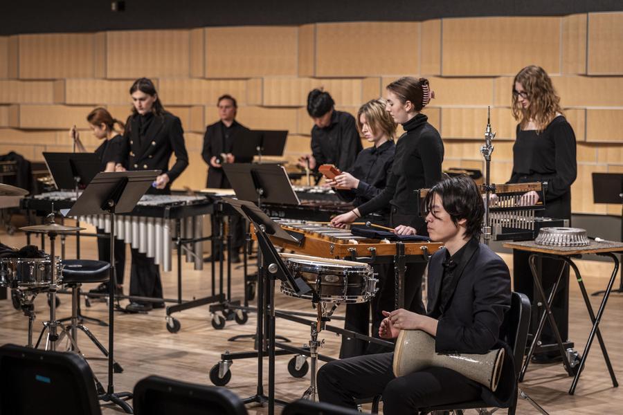 Percussion students dressed in black perform.