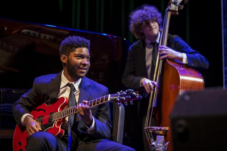 Two jazz musicians dressed in suits play electric guitar and double bass.