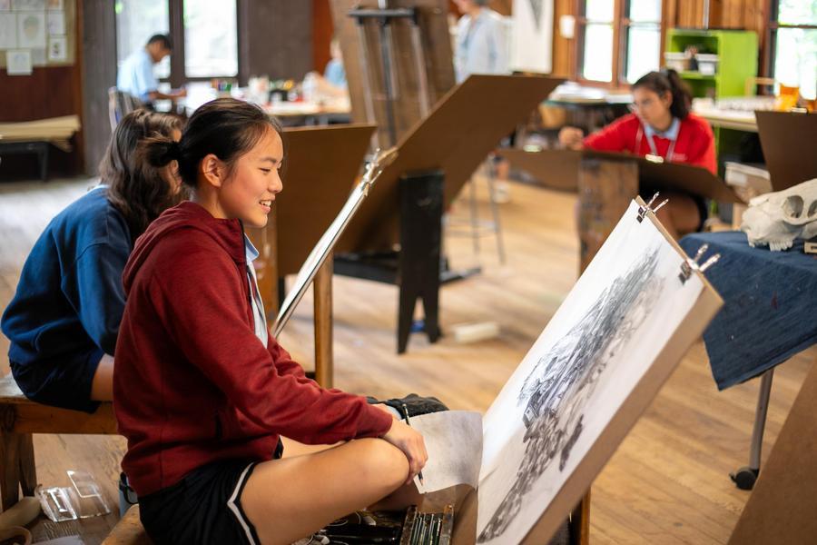 A student artist in a studio admires a drawing.