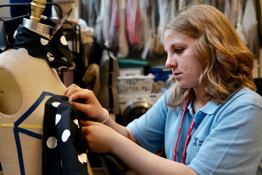 A student arranges patterned fabric around a dress frame.