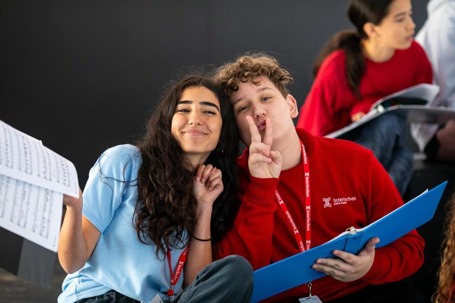 Two students holding music smile and pose for the camera.