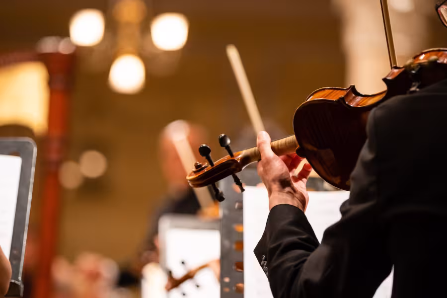 A violinist playing in an orchestra in a concert hall.