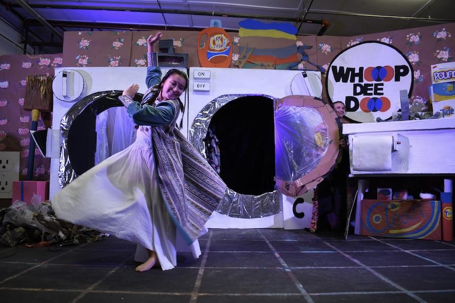 A student dances in front of a large pretend washer and dryer.