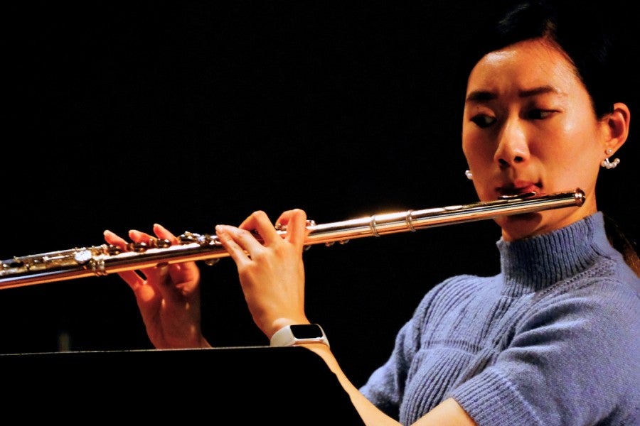 A woman playing flute on stage. 