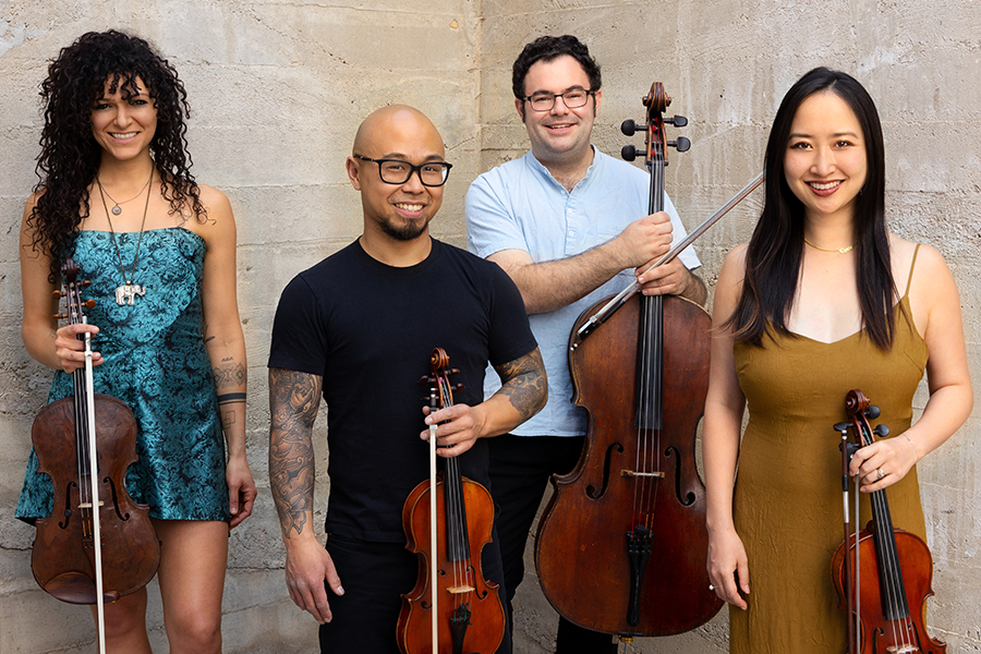 four musicians pose together with their respective string instruments
