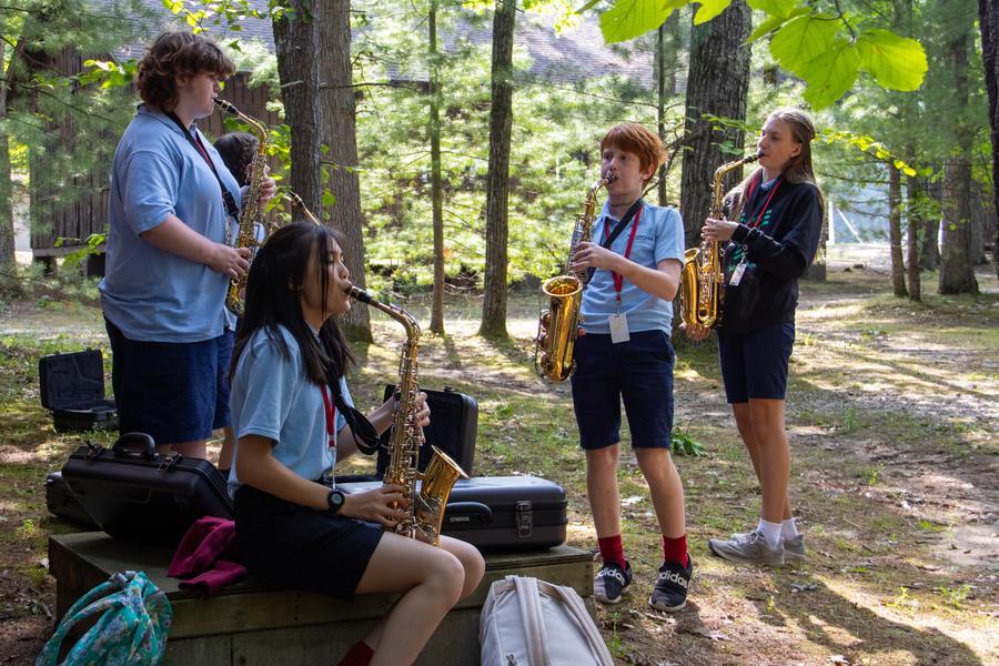 Four students in Camp uniforms play saxophones.