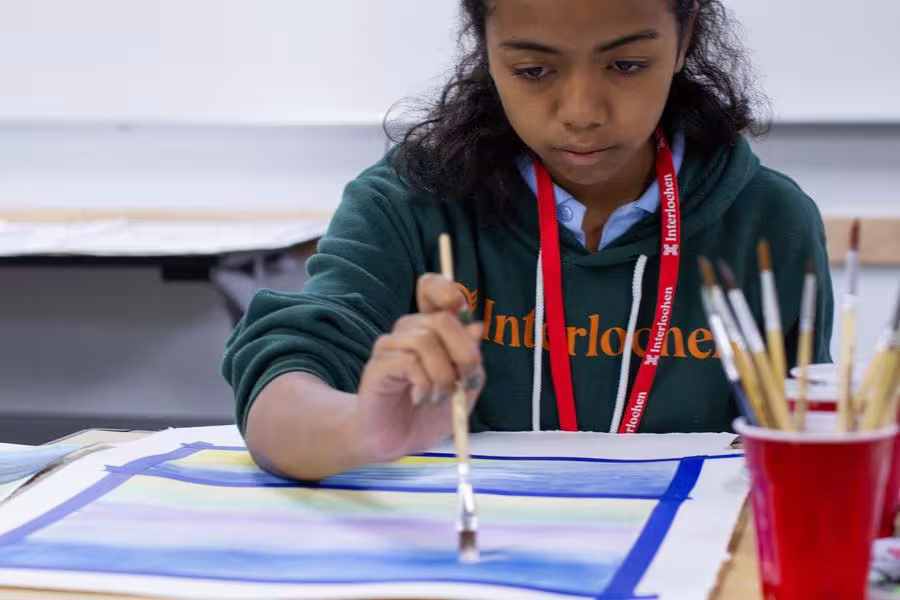 A dark-haired Intermediate student works on a painting.
