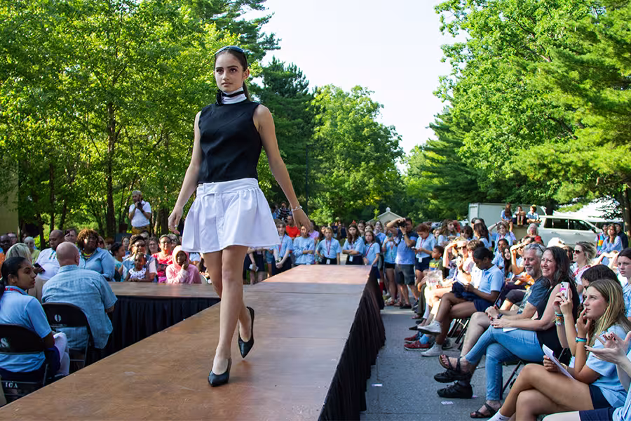 a student walks down a runway with student made fashion