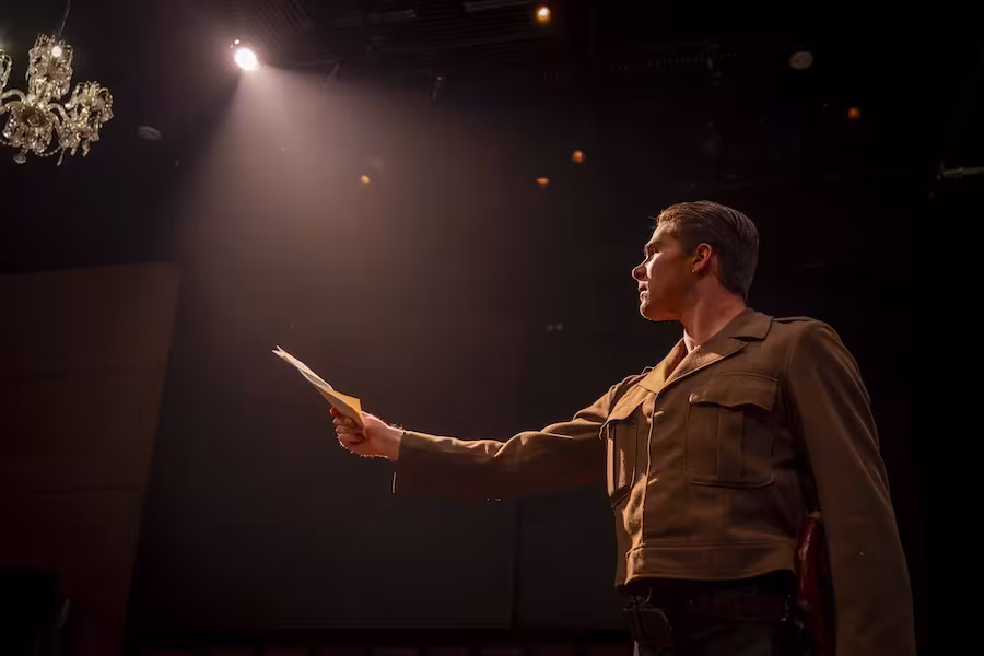Young man outstretching his hand with a paper as he looks at it with a spotlight on him