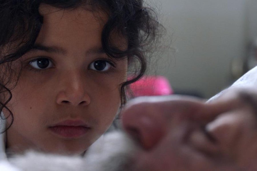 A young girl looks intently at a man's face