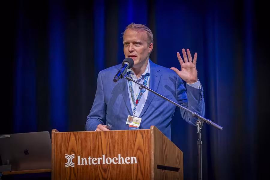 A man in a blue suit speaks from a podium.