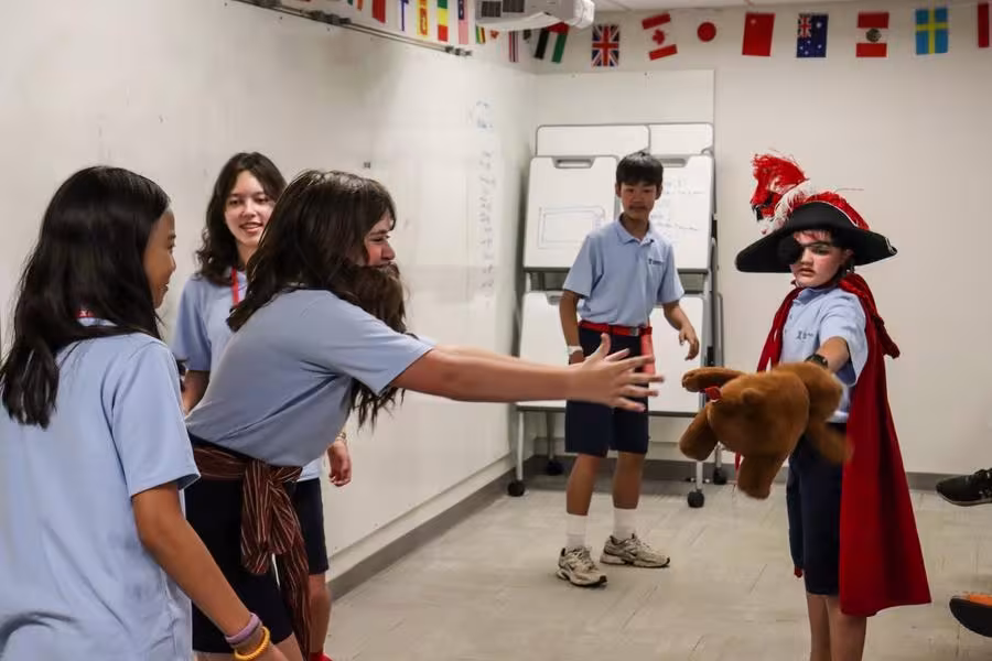 A student wearing a beard gestures dramatically toward another student dressed as a pirate.