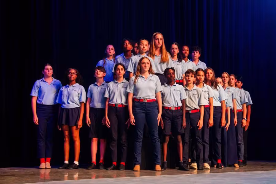 A large group of students stands in formation on stage.