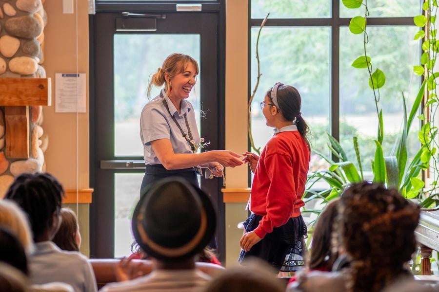A creative writing student shakes hands with an instructor in front of an audience.