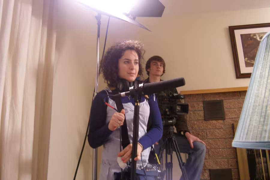 Sarah Nimeh stands behind a microphone on the set of a film. 