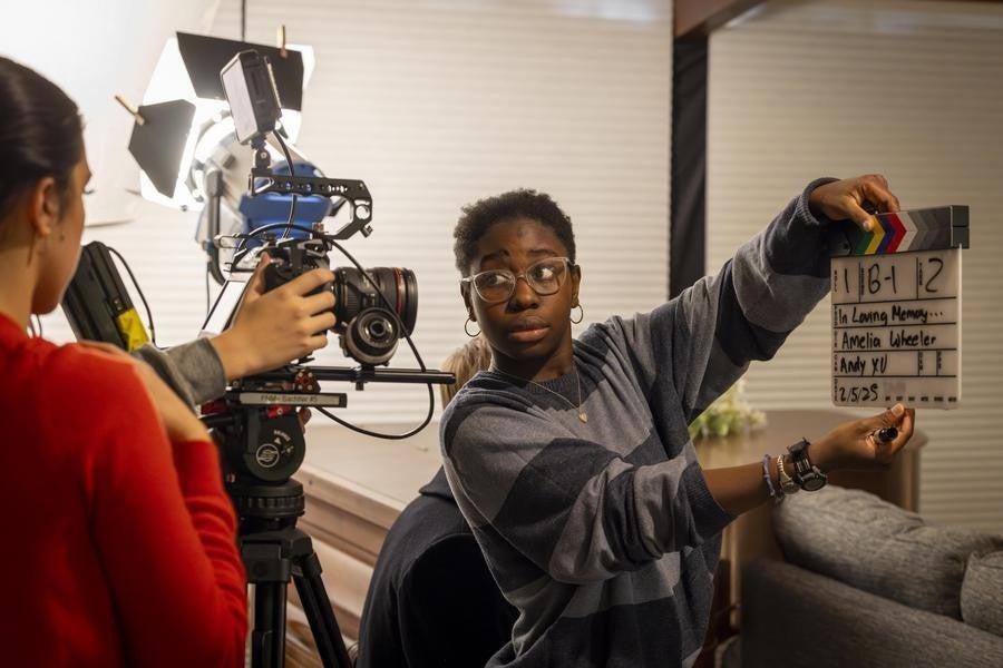 Two students with a camera and clapper prepare to start filming.