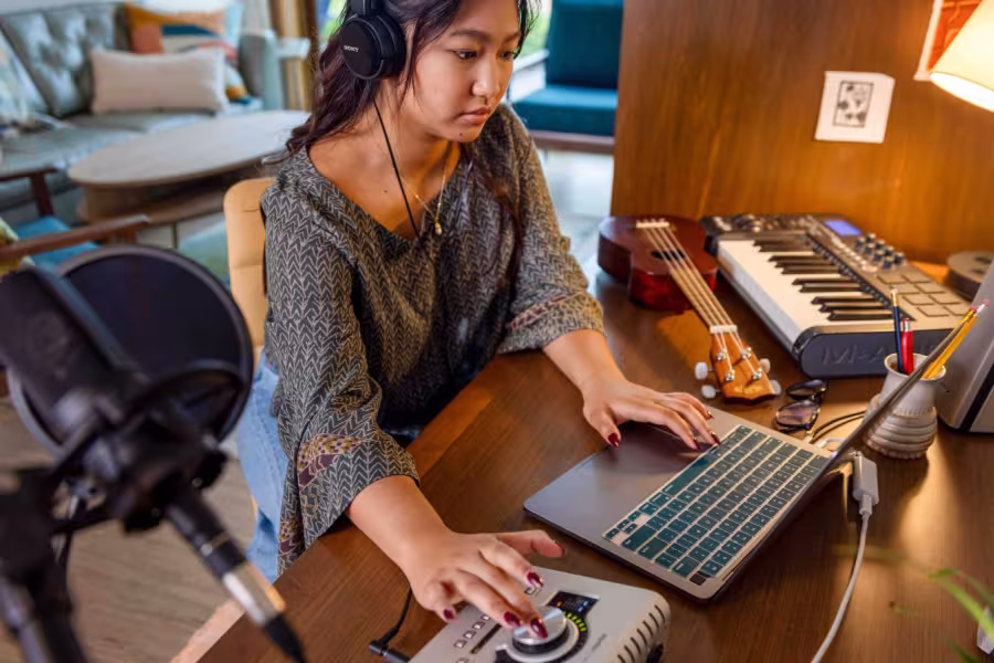 A girl at a computer with a microphone, headphones, and recording equipment.