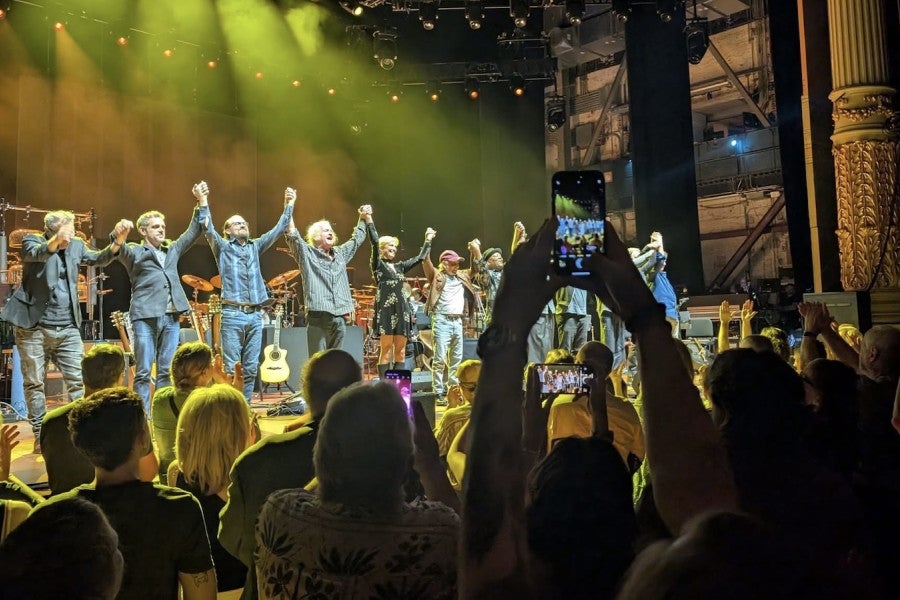 A band takes their bows onstage in front of a cheering audience.