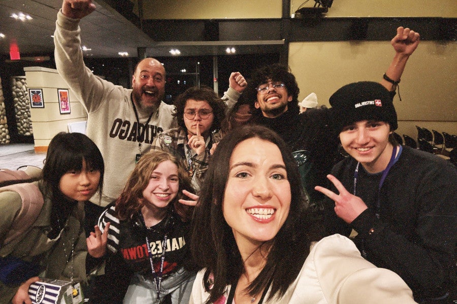A group of instructors and students smile and gesture excitedly.