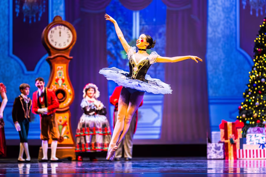A student wearing a tutu leaps into the air.