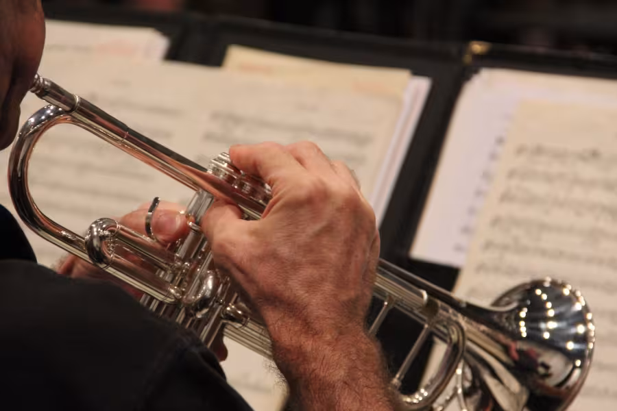 A man playing trumpet and reading sheet music