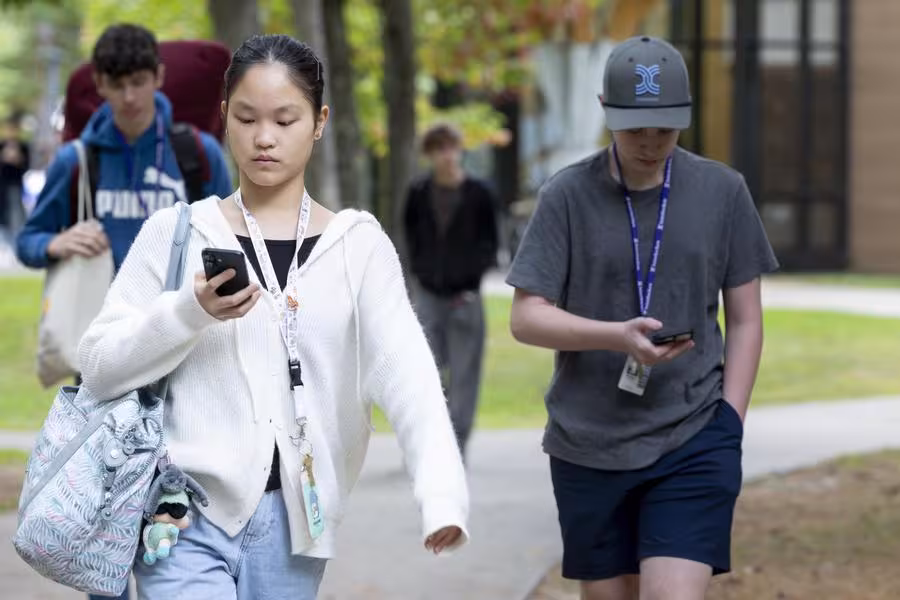 Students looking at their phones while walking to class