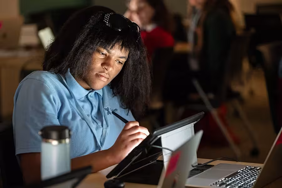 A digital animation student works diligently at a drawing tablet