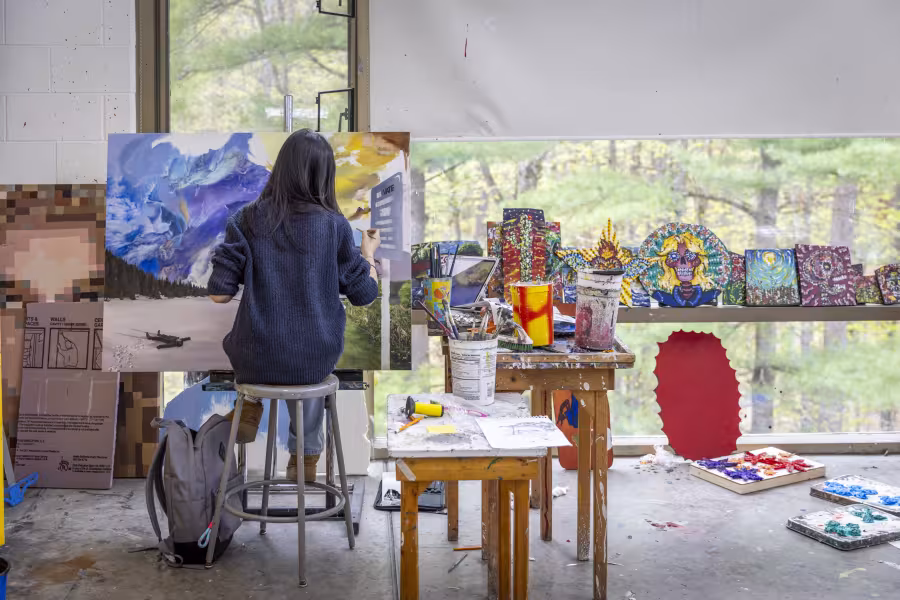 Student works on a painting in a paint studio